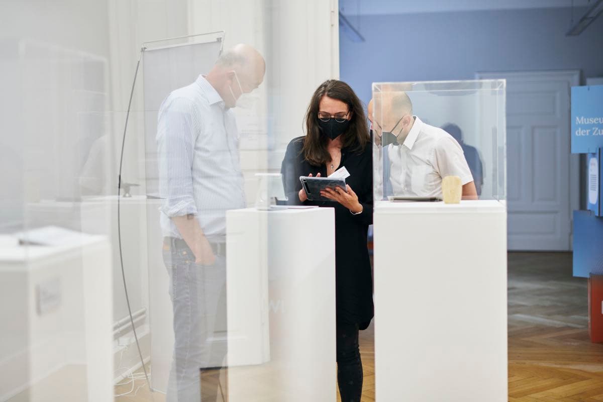 Drei Personen bedienen ein Tablet als Teil einer Ausstellung