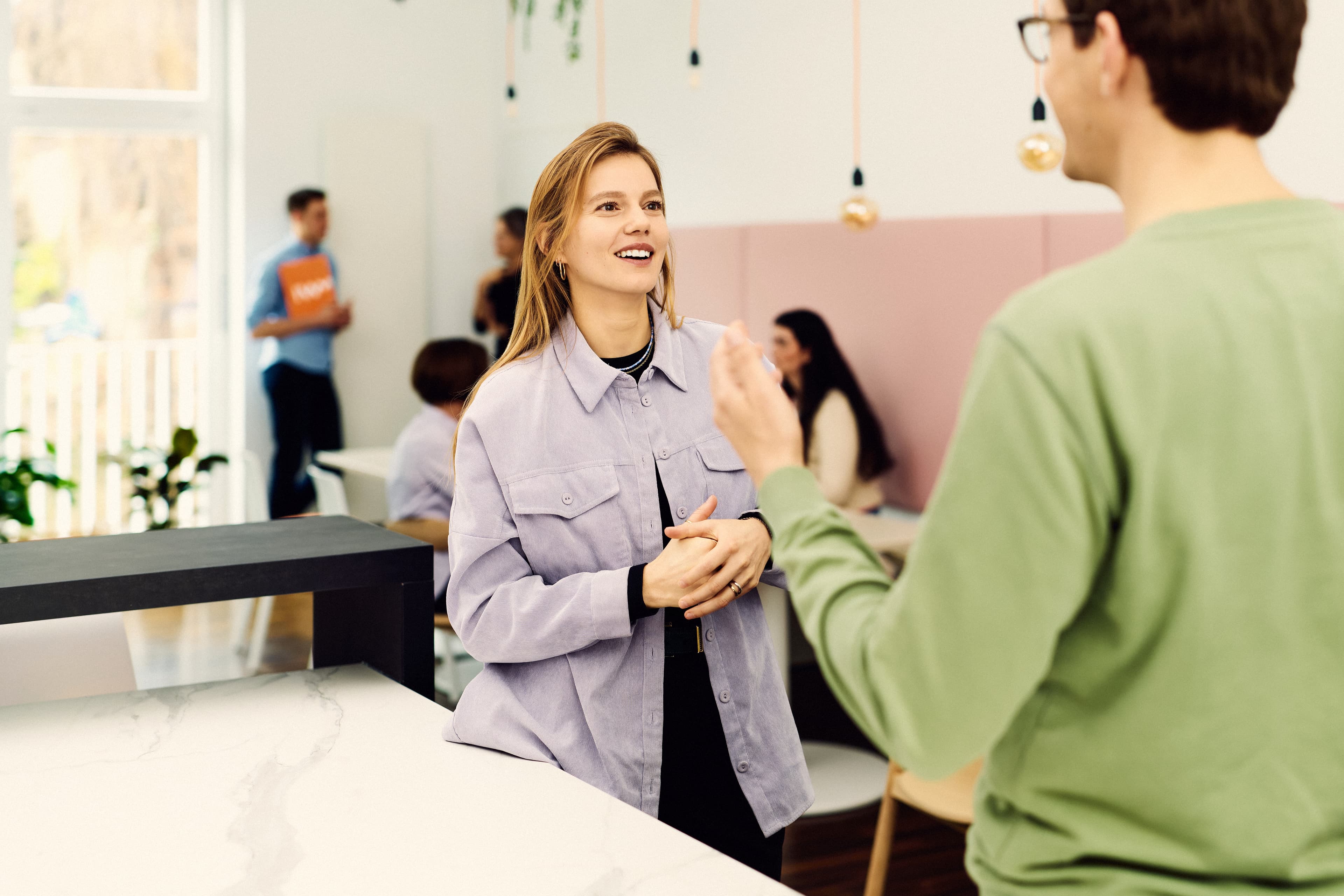 Zwei IWM-Mitarbeitende unterhalten sich an der Theke des Workcafés