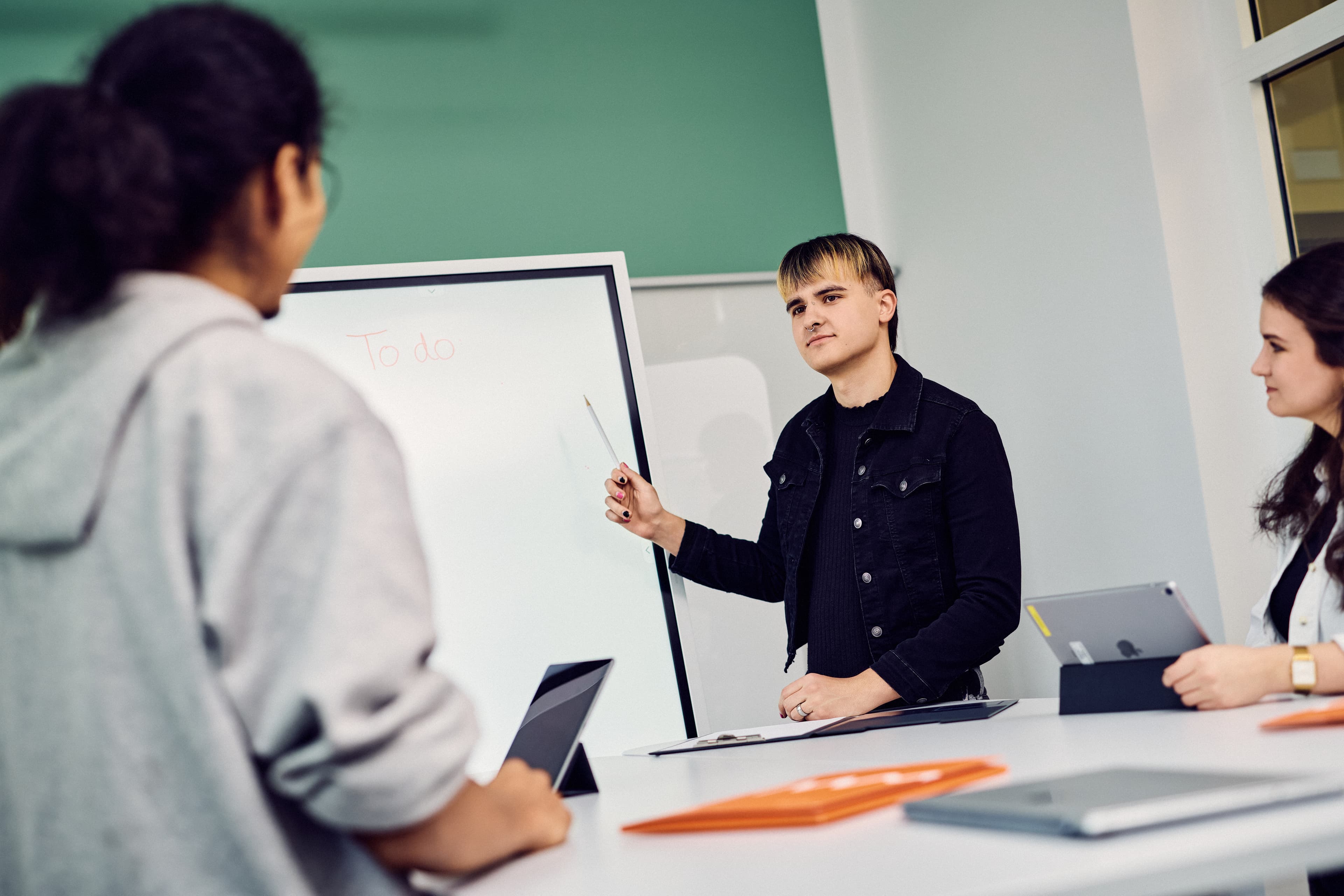 Eine Person zeigt zwei IWM-Mitarbeitenden etwas auf einem Whiteboard